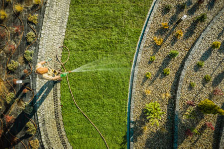 Gardening and Landscaping Industry Theme. Caucasian Garden Worker in His 40s Watering New Natural...