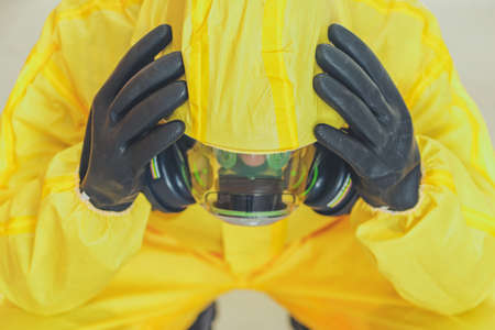Men in Yellow Hazmat Suit and Breath Protection Mask Loosing His Mind. Devastated Healthcare Worker Concept. Covid-19 Pandemic Mental Issues Theme.の写真素材