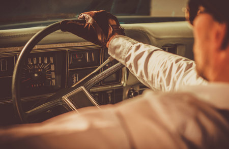 Classic Car Driver. Caucasian Men in His 40s Wearing Vintage Leather Gloves Driving His Aged Vehicle. History of Automotive Theme.の写真素材