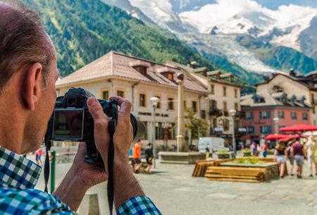 Caucasian Tourist in His 60s with Digital Camera Taking Picture While on Vacation. City of Chamonix...