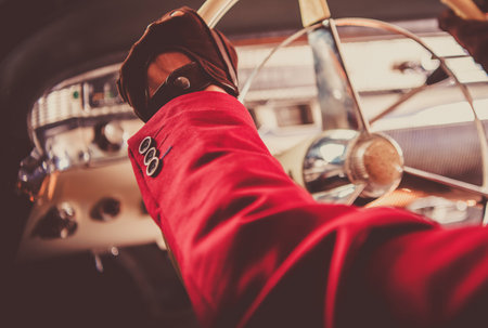 Classic Car Collector Driving His Vintage Car. Hands on the Vehicle Steering Wheel Close Up....