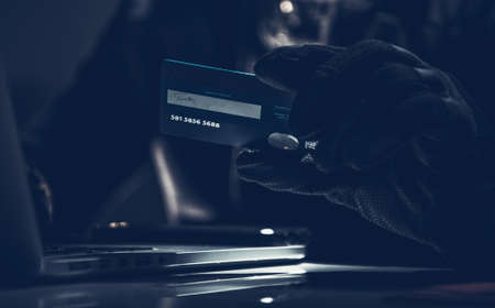 Stolen Credit Card in Thief's Hands in Dark Blue Illuminated Place. Fraud Committed Using a Payment...