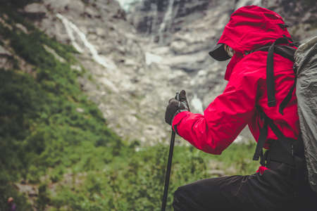 Alpine Trailhead Hiker in Red Raincoat Taking Short Break Before Attacking Summit of the Trail....