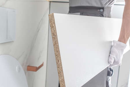 Worker Assembling Elegant White Painted Bathroom Furnitures Elements.