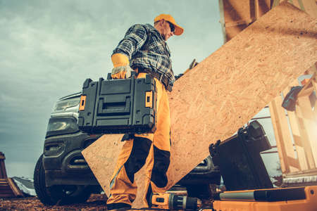 Caucasian Construction Worker in his 40s Moving His Tools Inside Construction Zone From His Pickup...