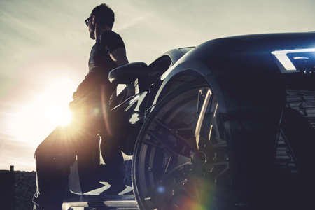Successful Men and His Luxury Exotic Car. Summer Time Road Trip and Sunset Scenery. Moren Automotive Theme.の写真素材