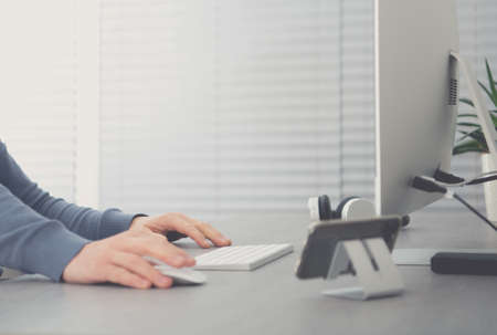 Men Behind Office Desk Working on His Desktop Computer. Left Top Copy Space Area. Corporate Theme. Clean and Elegant Office Interior.の写真素材