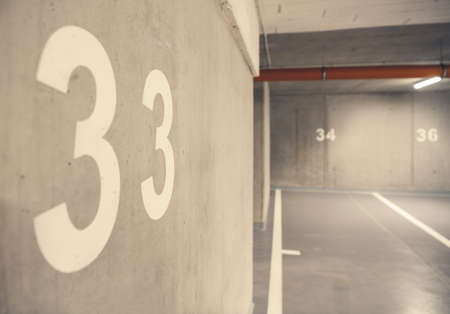 Residential Underground Car Garage Spaces Made Fully From Concrete. Space Numbers Painted on Building Walls.の写真素材
