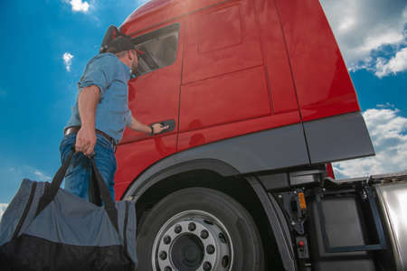 Euro Semi Truck Driver Going For Another Long Haul Across Europe. Caucasian Trucker with Handbag...