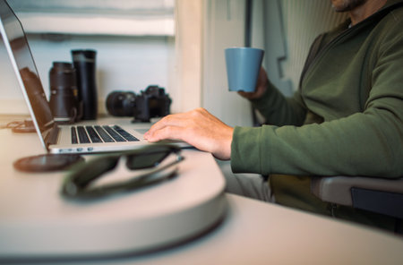 Caucasian Men in His 40s Remotely Working While Travel in a Motorhome. Remote Computer Work From a Camper Van.の写真素材