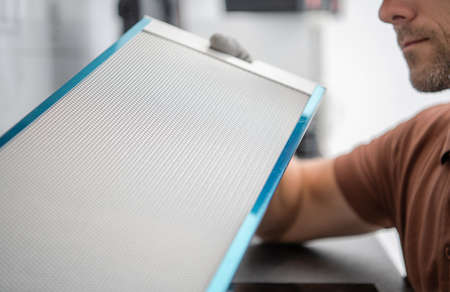 Kitchen Stove Hood Filter Replaced by Caucasian Men. Home Appliances Maintenance Theme.の写真素材