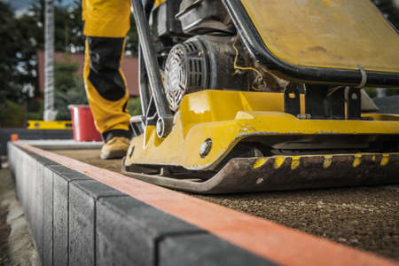 Worker with Soil Compactor Preparing Ground For Paving. Heavy Duty Construction Machinery.