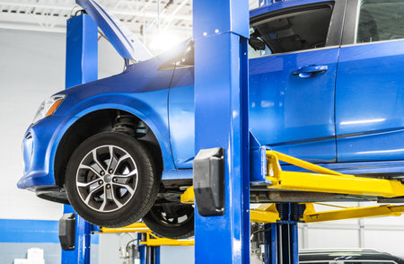 Automotive Industry Theme. Modern Blue Compact Car Maintenance on a Lift.の写真素材