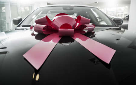 Car Sales Business. Brand New Elegant Car with Large Pink Gift Bow. Perfect Automotive Present.の写真素材
