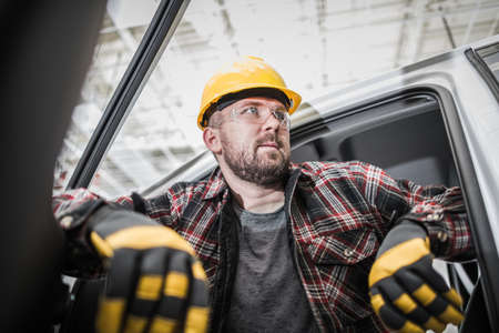 Caucasian Construction Site Contractor Worker in His 30s Inside His Pickup Truck. Men Wearing Safety...