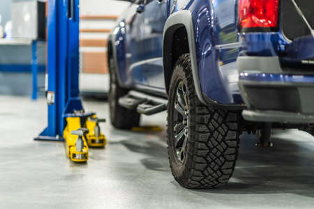 Auto Service Center and Broken Car on an Automotive Lift. Mechanic Solving Mechanical Issues.