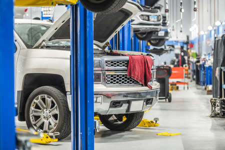 Car Dealership Auto Service Area. Clients Vehicles on Automotive Lifts Under Maintenance. From Oil...