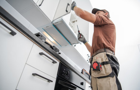 Residential Cabinetmaker Worker in His 40s Finishing New White and Modern Kitchen Cabinets Installation.の写真素材