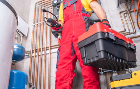 Residential Furnace System Technician at Work. Check and Repair HVAC Systems. Worker with His...
