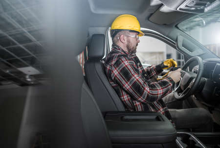 Caucasian Construction Worker Wearing Hard Hat and Gloves Inside Commercial Pickup Truck Inside a...