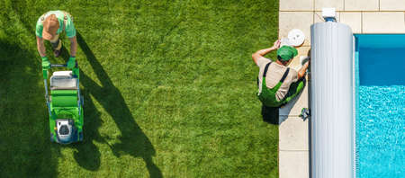 Two Garden and Landscaping Workers Performing Backyard Maintenance. One Men Trimming Grass Using...