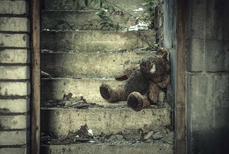 War Crimes Against Humanity Concept with Damaged Half Burned Teddy Bear Inside Residential House Ruins.の写真素材