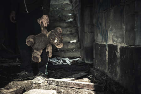 Direct Attacks Against Civilians During War Concept. Caucasian Male with Dirty Teddy Bear Toy in His Hand.の写真素材