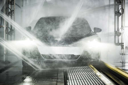 Modern Grand Touring Car Inside Powerful Touchless Car Wash. Front View. Automotive Technologies...
