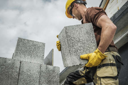 Hollow Dense Concrete Blocks Moved by Caucasian Construction Contractor Worker. Residential Construction.の写真素材