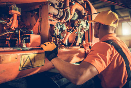 Caucasian Heavy Construction Equipment Mechanic in His 40s Repairing Bulldozer Engine.
