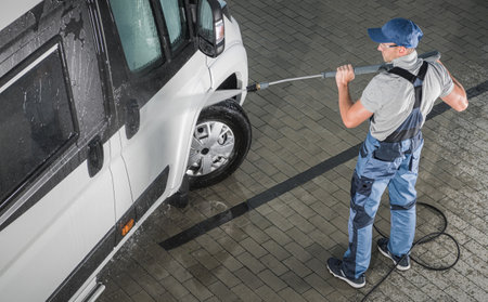 Caucasian Men Pressure Washing His Class B Recreational Vehicle Camper Van. Preparing His Motorhome For the Season.の写真素材
