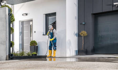 Caucasian Men in His 40s Cleaning His House Surrounding Using Powerful Pressure Washing Machine. Modern Washer in Action.の写真素材