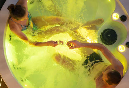 Caucasian Couple in Their 40s Having Great Time Inside Their Garden Hot Tub Bath. Drinking Champagne. Top View.の写真素材