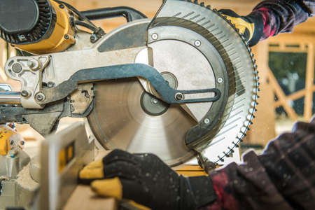 Construction Worker Cutting Piece of Wood Beam Using Large Circular Wood Saw Close Up