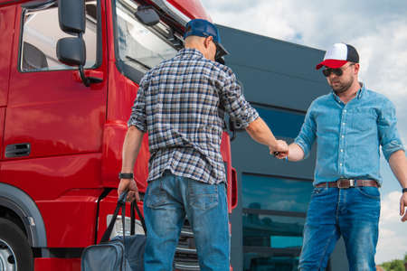 Meeting of Two Lorry Drivers In a Parking Lot to Swap Shifts. Man Passing the Keys of Red Semi Truck...