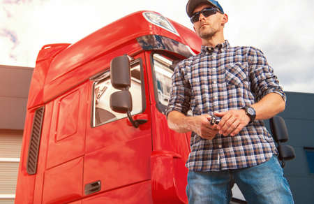 Caucasian Trucker in His 40s Proudly Standing in Front of Red Cabin of His Heavy Goods Vehicle...