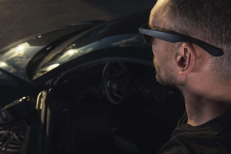 Caucasian Driver Wearing Black Stylish Sunglasses Staying Next to His Supercar. Going for a Road...