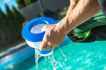 Caucasian Men Removing Chemical Dispenser From His Outdoor Swimming Pool To Load New Chlorine Tables. Water Treatment Theme.の写真素材