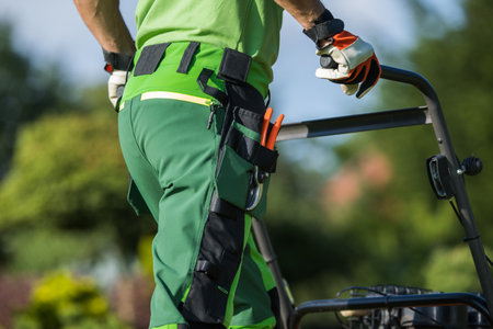 Caucasian Gardener Standing Backwards in Working Uniform with Garden Scissors in the Pocket Pushing...