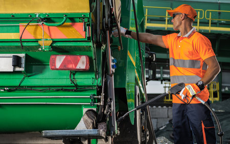Garbage Truck Worker with Pressure Washer Lance in His Hands Staying Next to the Vehicle. Preparing For Washing.の写真素材