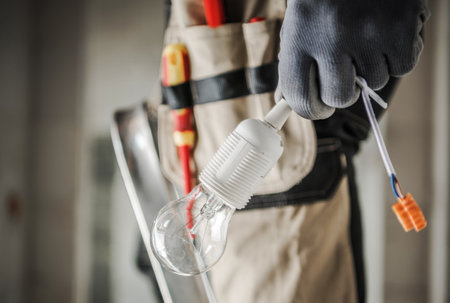 Electric Worker with Bulb in His Hand Preparing For a Light Point Installation. Close Up Photo....