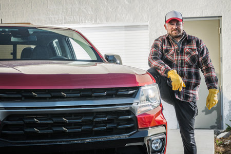 Professional Caucasian Mechanic Standing Next to Red Pickup Truck with a Smile on His Face. Happy...