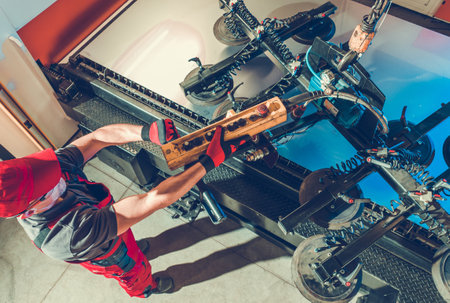 Caucasian Metalworking Industry Worker Using Vacuum Lifting Device To Move Sheet of Metal Into Laser Cutter. View.の写真素材