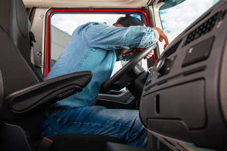 Side View of Tired Truck Driver Sleeping on Steering Wheel Inside Vehicle Cabin After Completing the...