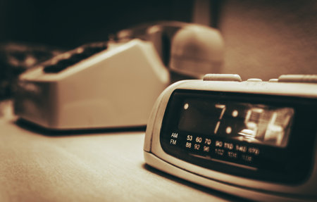 Vintage Hotel Room alarm Clock and the Analog Phone Close Up. Sepia Color Grading.の写真素材