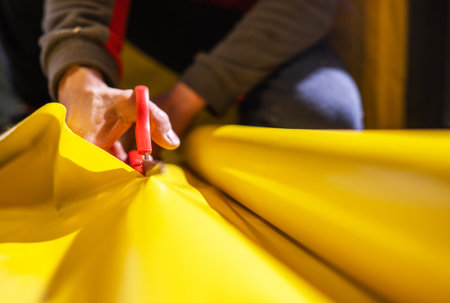 Part of House Wall Insulation Breathable Film Cutting To Size by Construction Worker Close Up.の写真素材