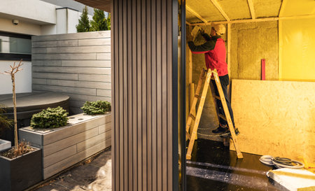 Caucasian Man in His 40s Insulating Newly Built Garden Shed with Mineral Wool. Walls Insulation Performed by General Contractor.の写真素材