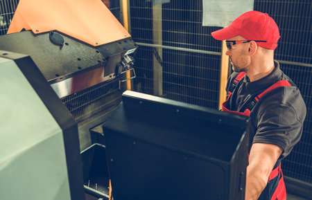 Professional Caucasian Machinist in Red Uniform Operating Industrial Machine at Manufacturing...