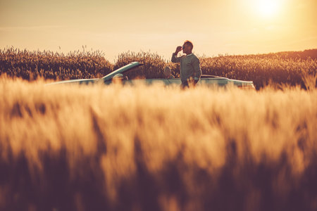 Relaxed Caucasian Man Staying Next to His Modern Convertible on a Country Road During Sunset Scenery. Summer Road Trip.の写真素材