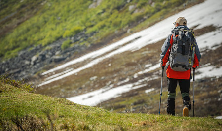 Back View of Professionally Equipped Hiker with Backpack and Trekking Poles on Mountain Trail. Hiking, Trekking and Backpacking Theme.の写真素材
